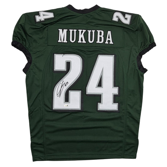 Back view of green pro cut football jersey with "MUKUBA" and number 24 in white, featuring an autographed signature on the chest.