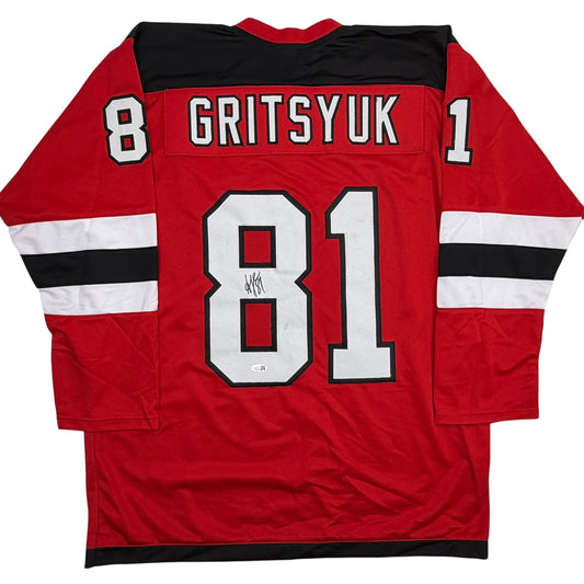 Back view of red hockey jersey with "GRITSYUK" and number 81 in white lettering, signed in black marker.