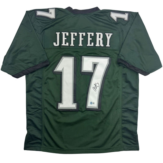 Green football jersey displaying "JEFFERY" and number "17" with autographed signature on number, flat lay front view.