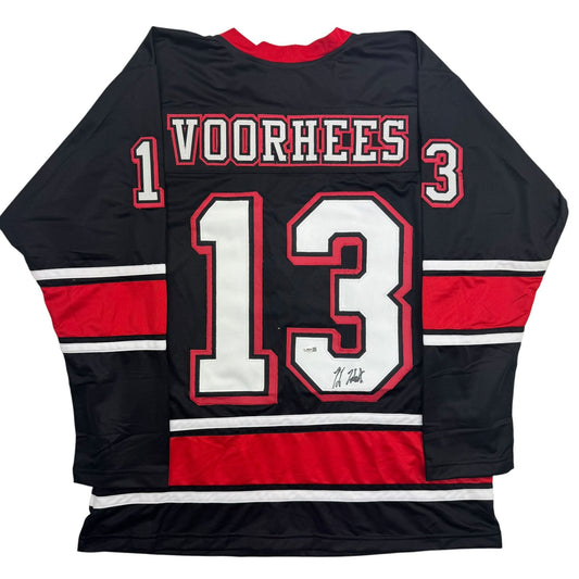 Back view of black hockey jersey with red and white stripes featuring "VOORHEES" and number 13 with signature.