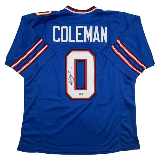 Back view of blue football jersey with "COLEMAN" and number "0" in white and red, featuring red and white striped sleeves and signature.