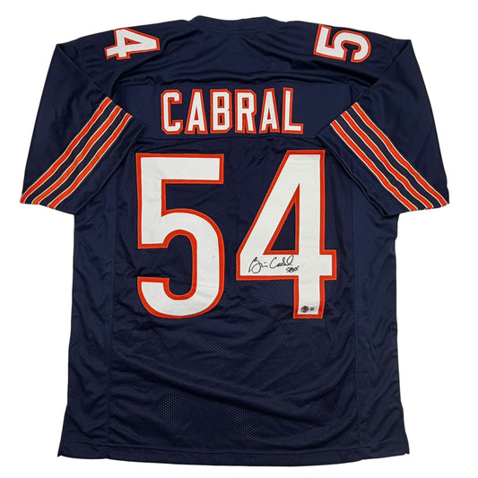 Back view of navy blue football jersey number 54 with red and white "CABRAL" nameplate and autographed number.