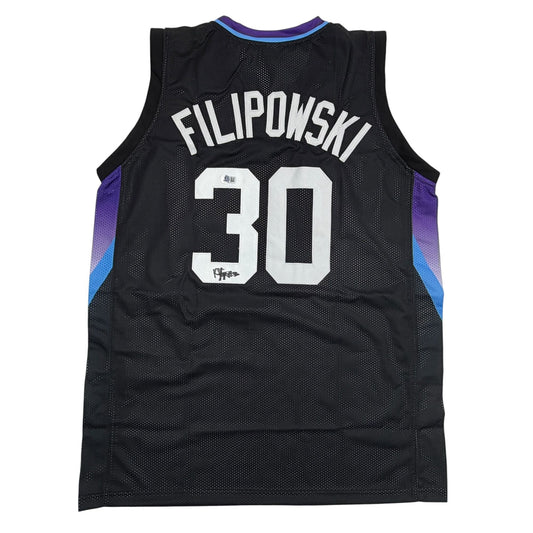 Back view of black mesh basketball jersey with purple and blue side panels, white "FILIPOWSKI 30" text, and visible autograph on number.