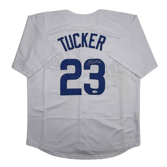 White baseball jersey displayed flat, back view showing "TUCKER" and number "23" in navy blue with autographed signature on the number.