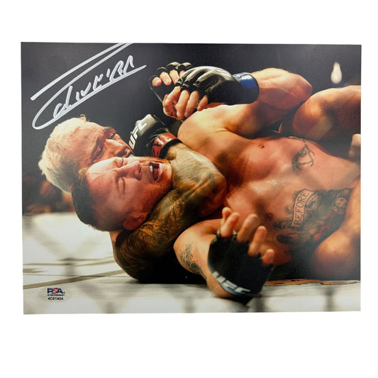 Signed photograph of UFC fighter in ground combat position wearing black gloves and shorts with visible tattoos on mat.