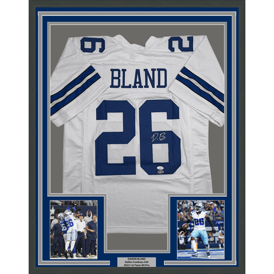 Framed white Dallas Cowboys #26 jersey signed by Daron Bland with two action photos and nameplate below.