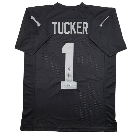 Back view of black mesh football jersey with "TUCKER" and number "1" in white, autographed across chest area.
