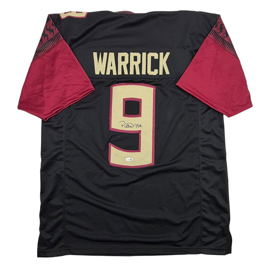 Black and maroon Florida State football jersey numbered 9 with "WARRICK" across shoulders, displayed flat, showing autographed signature on cream-colored number.