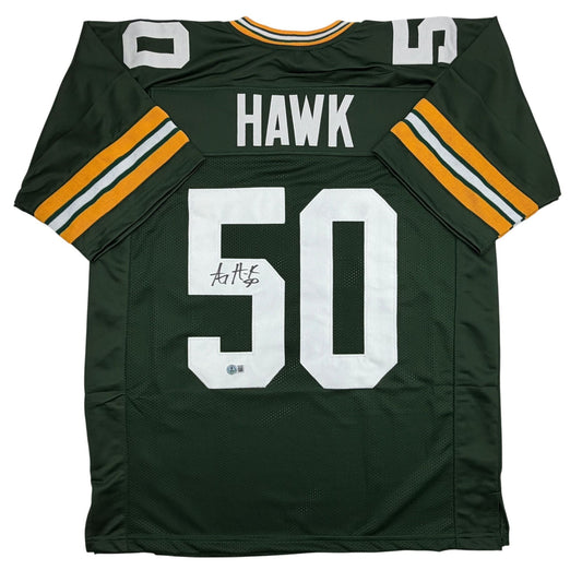 Flat lay of signed green and gold Green Bay Packers jersey number 50 with "HAWK" nameplate and autograph.