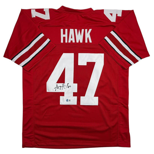 Red college football jersey displayed flat featuring "HAWK" and number 47 with white stripes on sleeves and autographed signature.