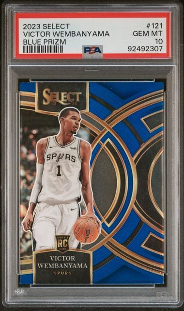 Graded basketball card in clear PSA case displaying Victor Wembanyama in white Spurs jersey against blue and gold geometric design.