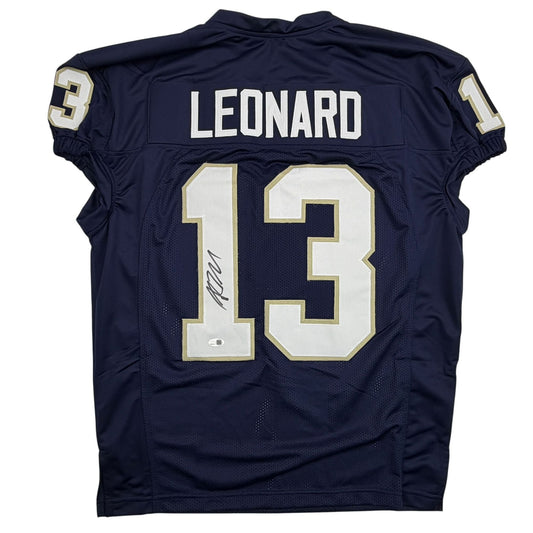 Back view of navy blue Notre Dame football jersey number 13 with "LEONARD" nameplate and autograph on white numerals with gold trim.