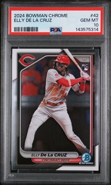 PSA-graded baseball card in clear plastic case showing Elly De La Cruz in red Cincinnati Reds uniform mid-swing against dark background.