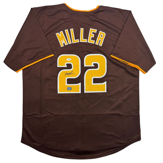 Brown baseball jersey with yellow number 22, "MILLER" nameplate, and autograph, displayed flat against white background.