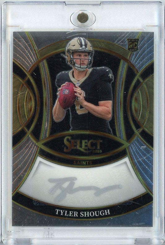 Front of graded football trading card featuring Tyler Shough in Saints uniform holding red football with ornate gold-bordered design and silver autograph.