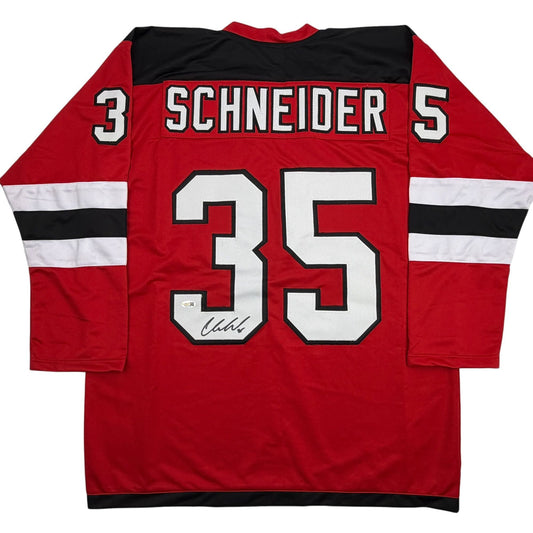Back view of red New Jersey Devils hockey jersey number 35 with "SCHNEIDER" nameplate and autographed signature on white numbers.