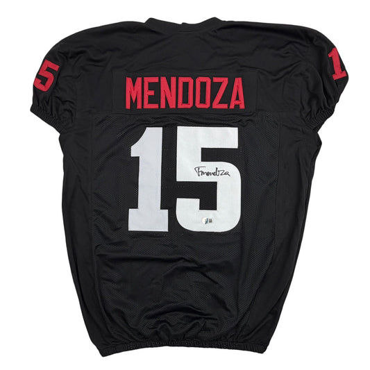 Back view of black college football jersey with red "MENDOZA" nameplate and white number 15, signed in black marker.
