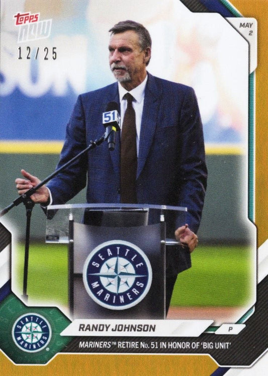 Randy Johnson in dark suit speaking at podium with Seattle Mariners logo during number retirement ceremony.