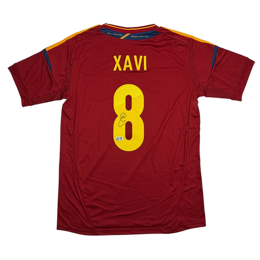 Back view of red Spain football jersey with yellow number 8 and "XAVI" nameplate, signed.