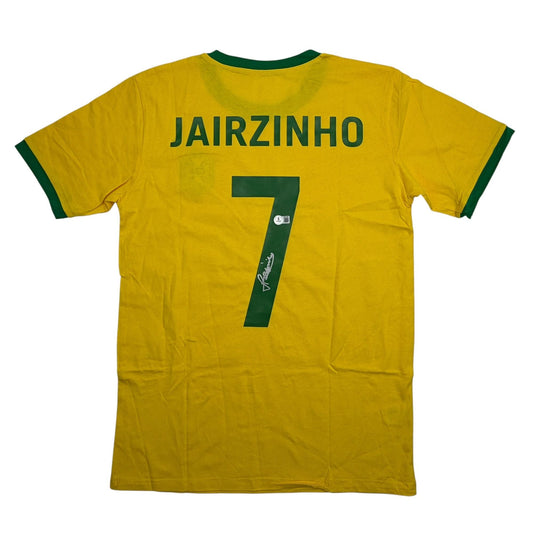 Back view of yellow Brazil soccer jersey with green trim, displaying "JAIRZINHO" and number 7 with autographed signature on the number.