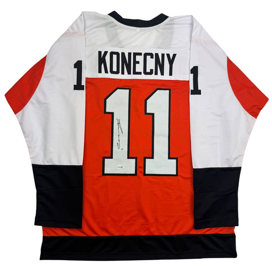 Back view of signed orange, white, and black hockey jersey with "KONECNY" and number "11" printed across shoulders and back.