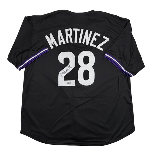 Back view of black baseball jersey with "MARTINEZ 28" in white lettering and purple sleeve trim, signed in black ink on the number.