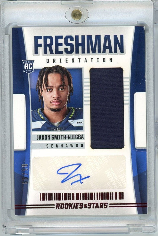 Graded rookie card in clear plastic case featuring Jaxon Smith-Njigba in Seahawks uniform with autograph and dark fabric swatch.