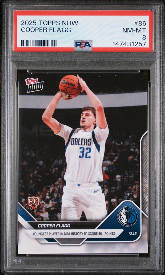 PSA-graded basketball card in plastic holder showing Cooper Flagg in Dallas Mavericks white jersey shooting basketball, red label with grading details visible at top.