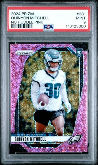 PSA-graded trading card in plastic case displaying Quinyon Mitchell in Eagles uniform on pink sparkly background with card details visible on label.