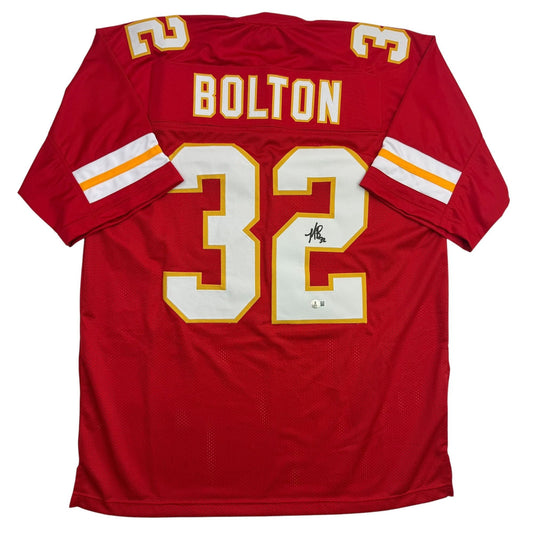 Back view of red Kansas City Chiefs jersey number 32 with "BOLTON" nameplate and visible autograph on white chest numbers.