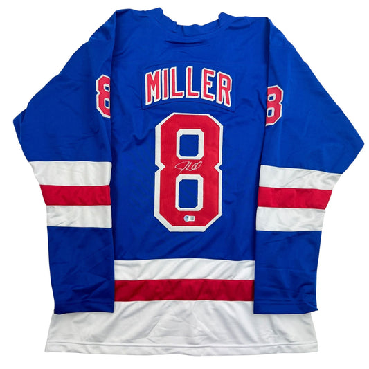 Blue hockey jersey with red and white stripes, displaying "MILLER" and number 8 with visible autograph on front.