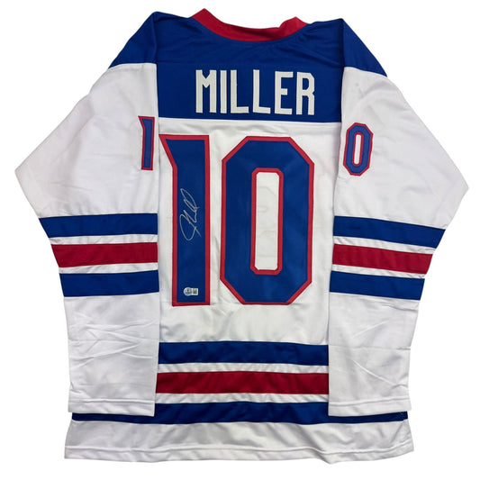 Back view of white hockey jersey with navy and red stripes, displaying "MILLER" and number "10" with visible autograph on the number.