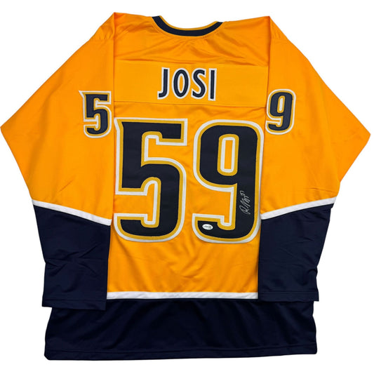 Back view of gold and navy hockey jersey displaying "JOSI" and number "59" with autograph signature visible on the chest.