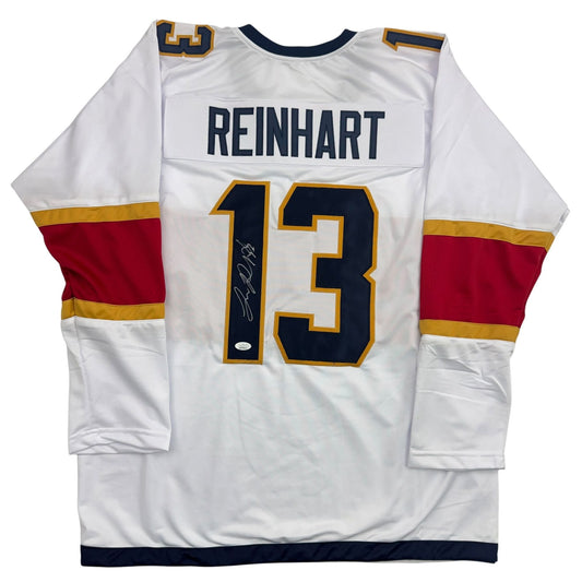 White hockey jersey with red and gold stripes, displaying "REINHART" and number 13 with autographed signature on back.
