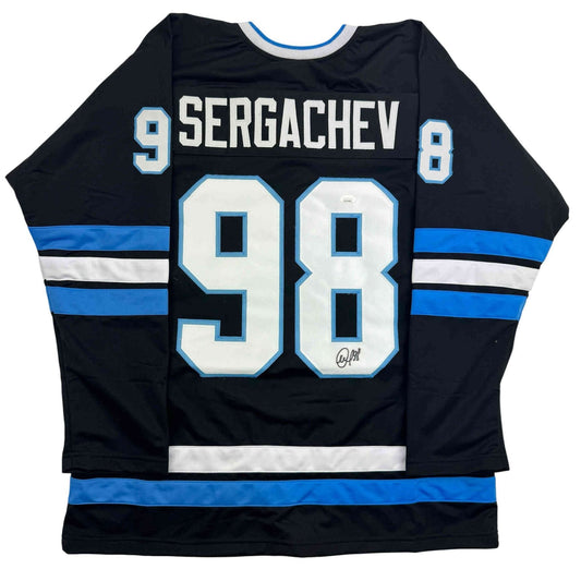 Back view of black hockey jersey with blue and white horizontal stripes, number 98, and "SERGACHEV" nameplate with autograph.