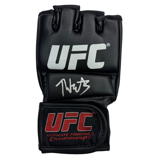 Black UFC fighting glove with white logo and red text, displaying handwritten signature on palm area.
