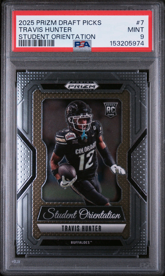 PSA-graded trading card in clear plastic case showing Travis Hunter in Colorado football uniform number 12, with gold-framed Prizm design and red grading label.