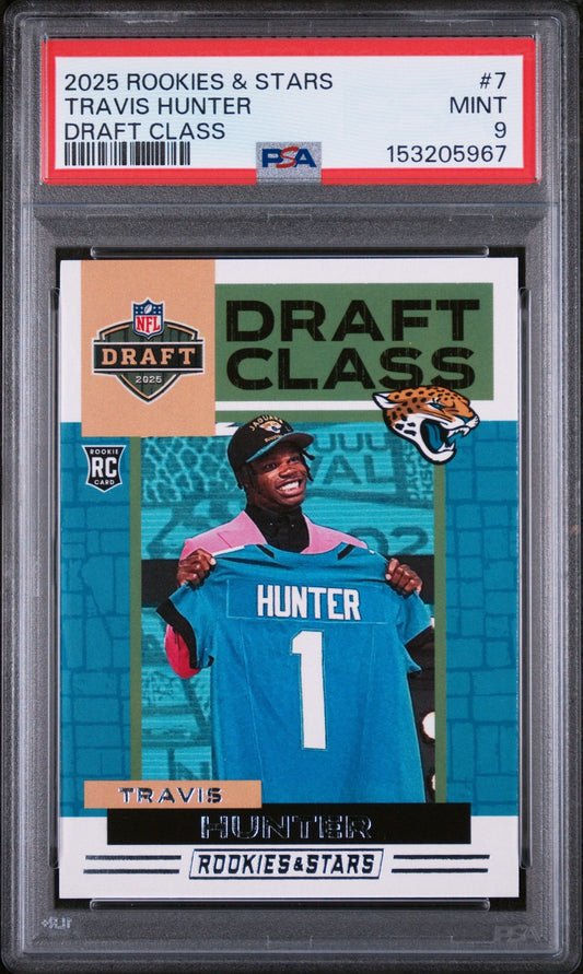 PSA-graded trading card in plastic case showing Travis Hunter in Jacksonville Jaguars uniform holding jersey number one.