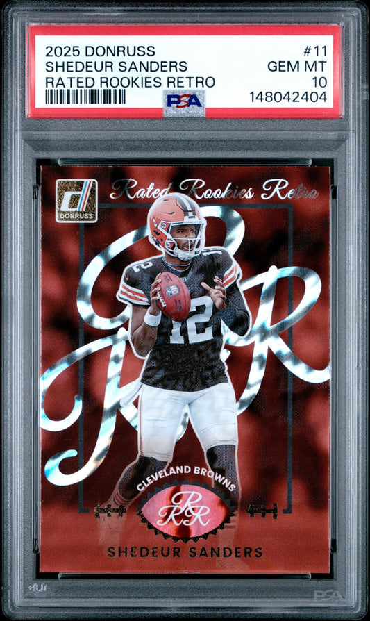 PSA-graded rookie football card showing Shedeur Sanders in Cleveland Browns uniform holding football against red background with decorative script overlay.