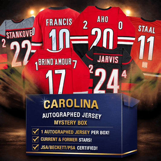 Six signed Carolina Hurricanes hockey jerseys displayed behind blue mystery box packaging with gold text on dramatic lit background.