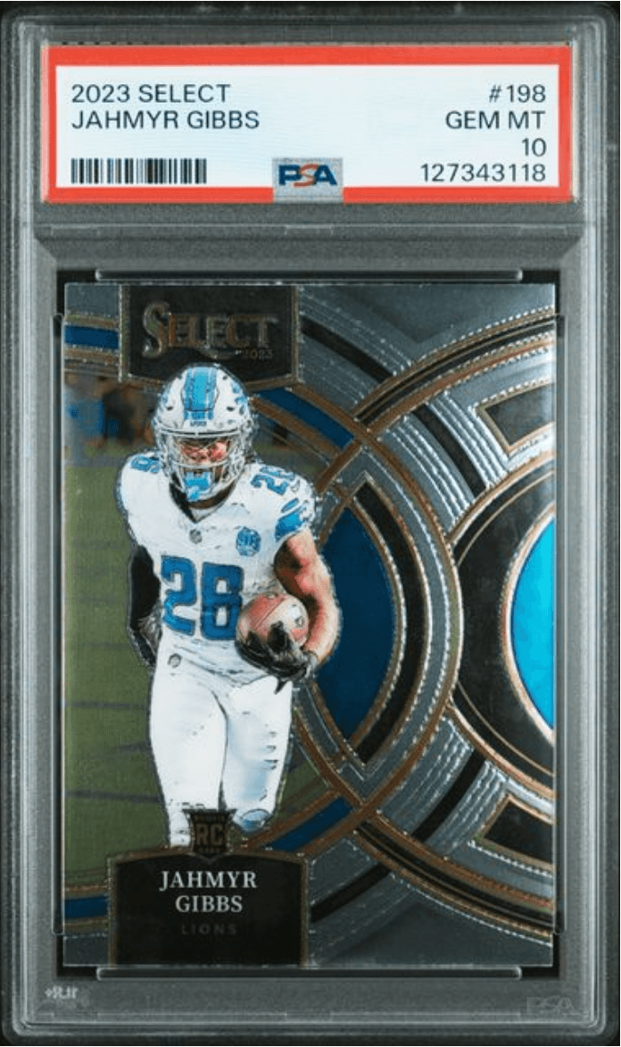 Front view of a graded card slab showing a Lions player in a white jersey with blue number 28, holding a football.