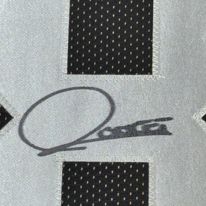 Close-up of a black ink signature with a looping oval on grey jersey fabric, between black perforated mesh panels.