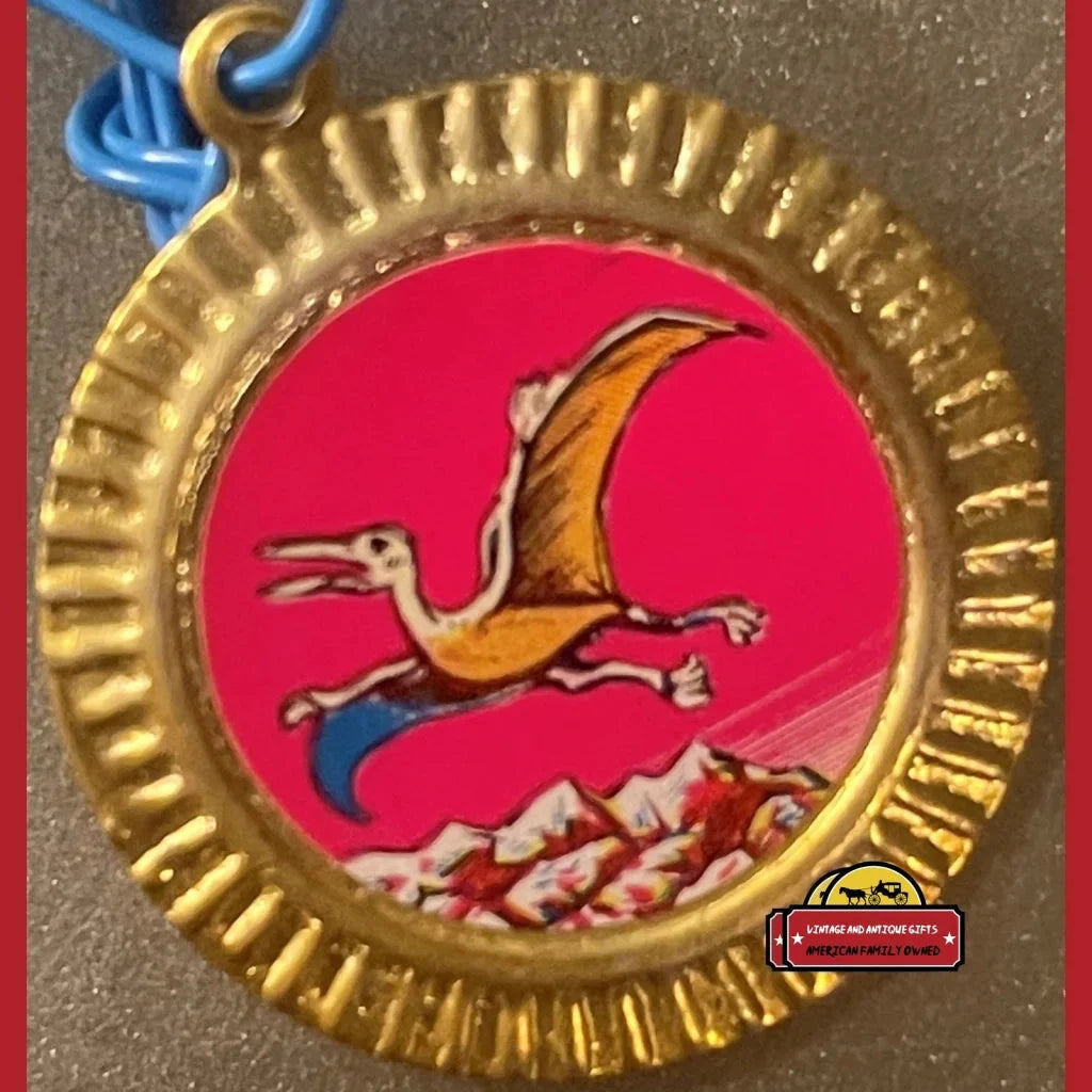 Gold medal with a pterodactyl over mountains, perfect for vintage tin dinosaur lovers