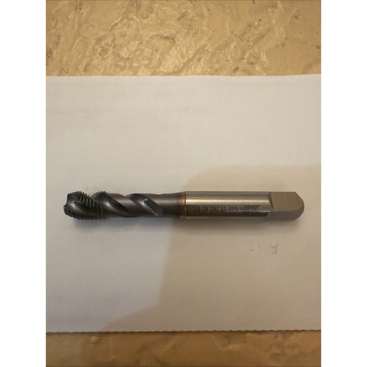 Haas 3/8-24 UNF spiral point tap displayed horizontally on white paper, showing black fluted cutting end and brass-colored shank with engraved markings.