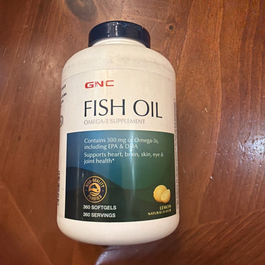 GNC Fish Oil supplement bottle with white label and dark blue cap sitting on wooden surface, front view.