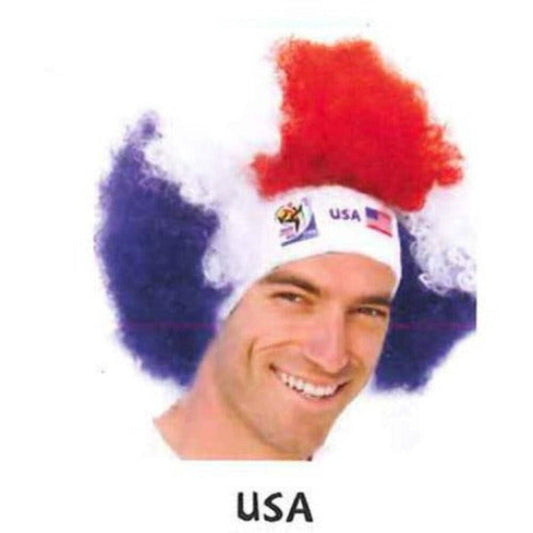 Man wearing red and blue afro wig with white USA headband featuring American flag logo, smiling at camera.
