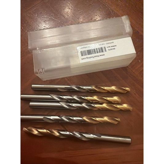 Five gold-coated carbide end mills displayed next to their clear plastic storage box with barcode label on wooden surface.
