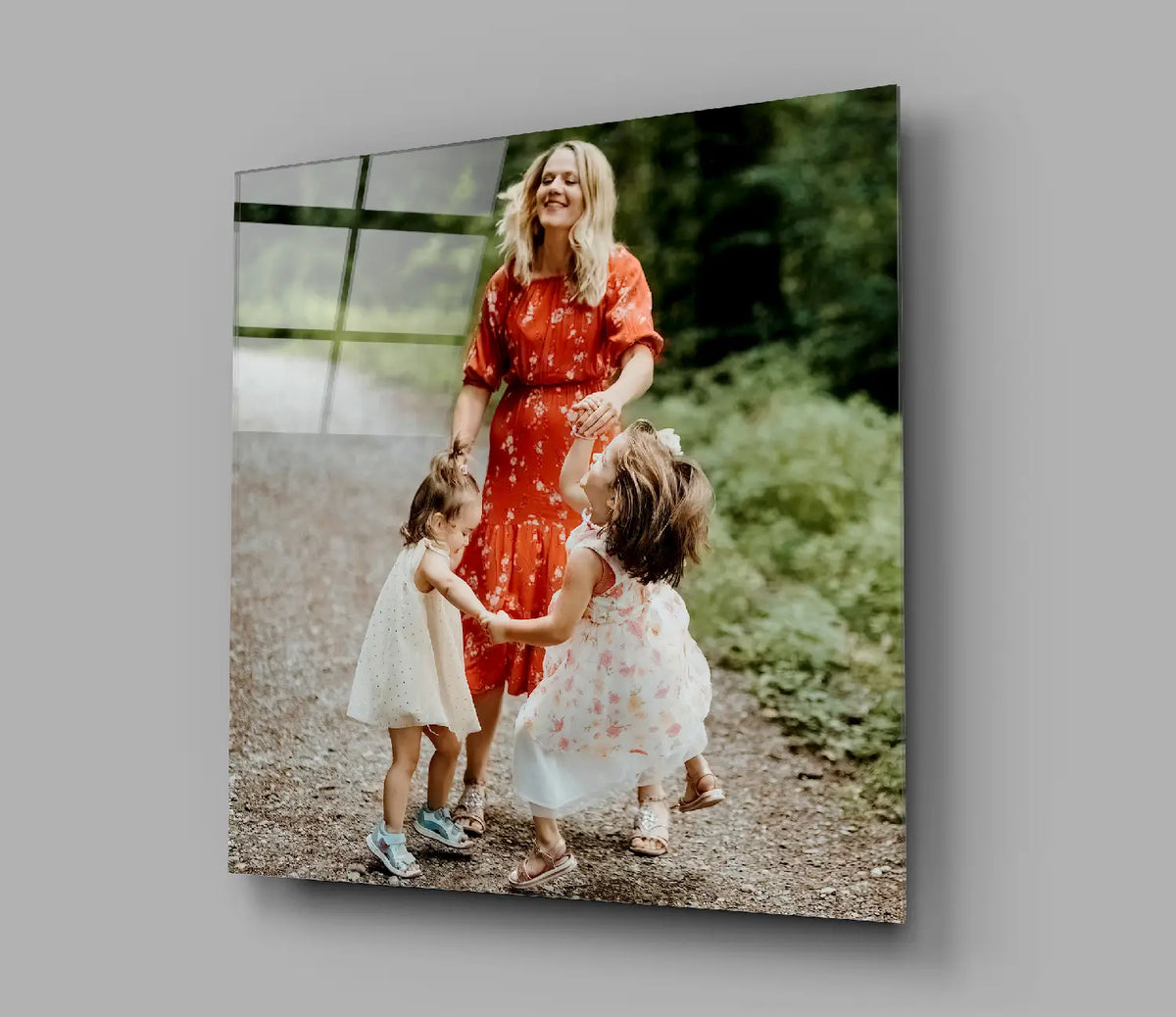 Woman in orange floral dress with girls in white on printed glass art