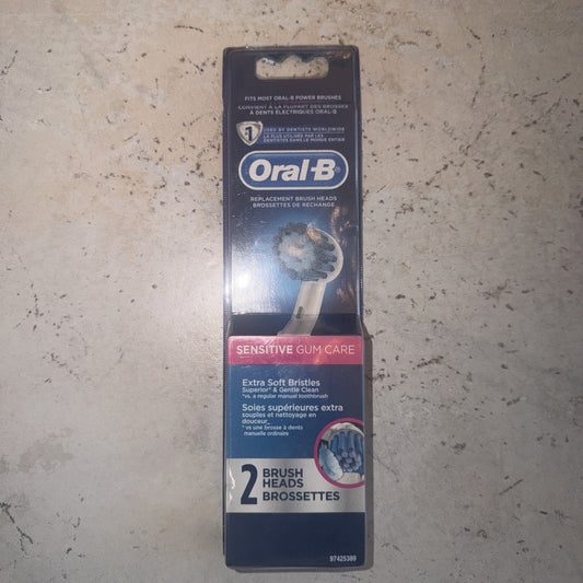Oral-B Sensitive Gum Care replacement brush heads package displayed flat on concrete surface, showing front packaging with blue and pink labeling and product details.