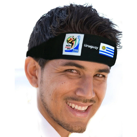Man wearing black headband with 2010 FIFA World Cup South Africa logo and Uruguay flag, smiling at camera.